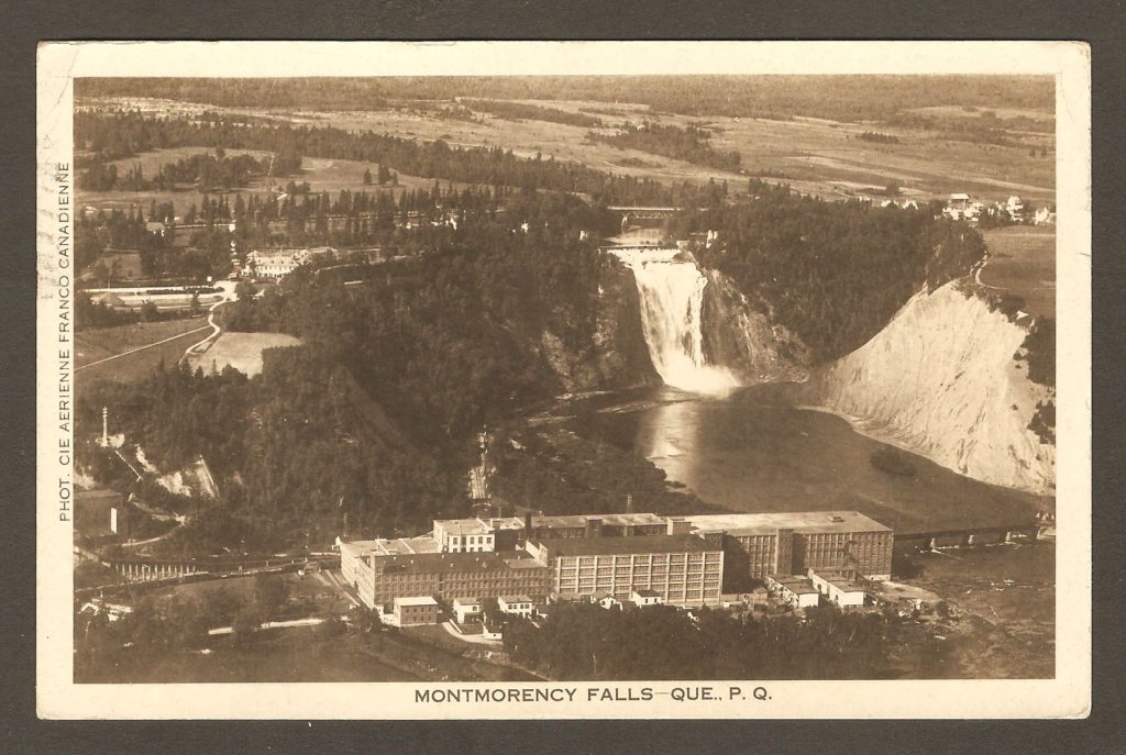 Photo aérienne de la Dominion Textile, avec la chute Montmorency en arrière plan, sur une carte postale datant des années 1930.