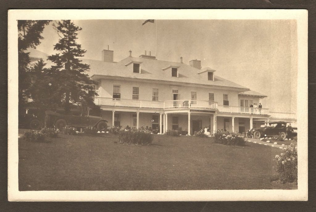 Une carte postale « photo réelle » montrant la façade du Kent House, vers 1925. Des automobiles d'époque sont stationnées devant l'hôtel et on remarque la présence de personnes sur le balcon donnant sur la salle de bal, à droite.
